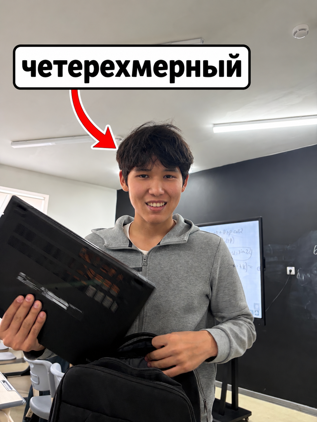 Человек с ноутбуком и рюкзаком в аудитории; на фото авторская подпись со стрелкой